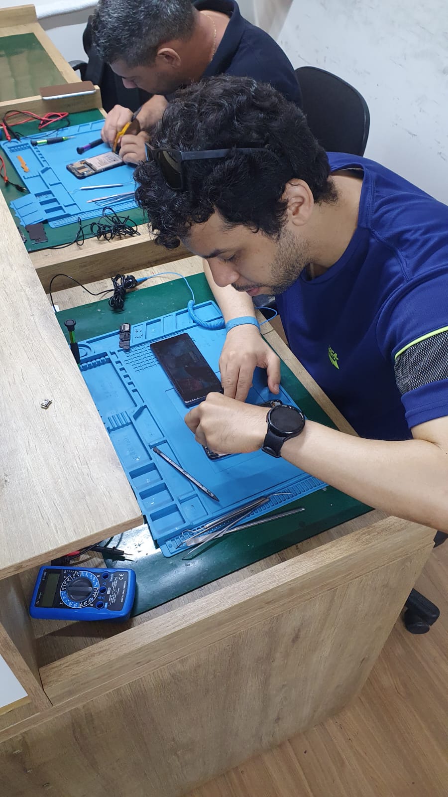 Alunos em bancada de reparo avançado de celulares